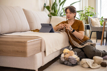 Feminine hipster man crochet handmade use hook knitting needles and wool yarn relaxing on couch