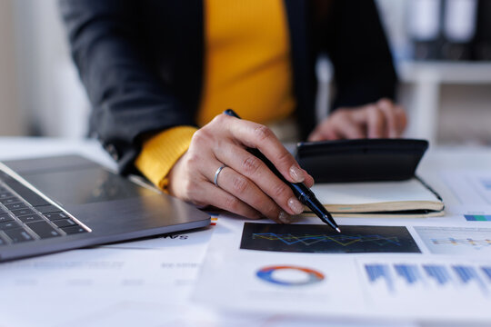 Business woman working on laptop, using tablet at modern office, analyzing business document with financial graph, market report on digital tablet, business data analysis concept
