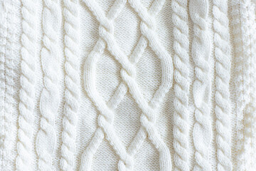 Close-up of white knitted wool sweater with cable pattern texture. Trendy color of 2026 year