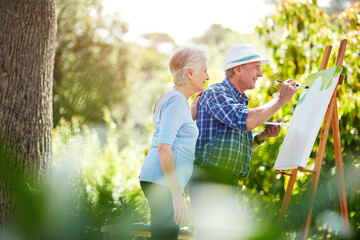 Naklejka premium Morning, painting and senior couple in park for bonding with artistic hobby, creativity and artwork. Retirement, marriage and elderly man and woman with canvas for drawing, picture and happy outdoor