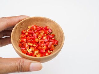 Ripe red bird's eye sliced in to pieces, sit in a wooden bowl on a white background. The are vegetables I grow naturally in my own garden.