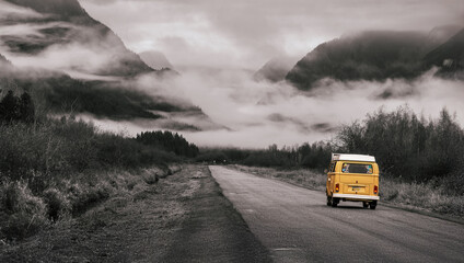 Yellow camper van road trip into misty mountains on lonely highway vanlife adventure wanderlust travel photography moody landscape foggy forest freedom to roam cinematic journey into wild nature
