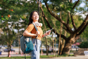Young asian woman student carrying backpack smiling outdoors
