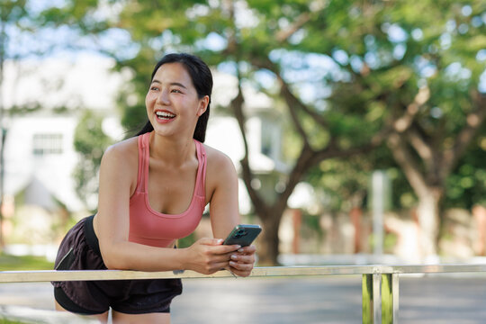 Young smiling woman holding phone taking outdoor break