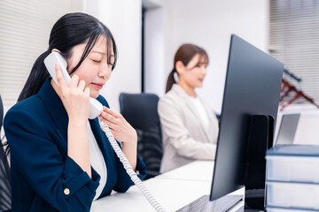 Fototapeta premium オフィスでお詫びの電話をする若いキャリアウーマン