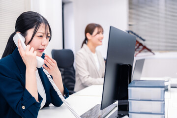 オフィスでお詫びの電話をする若いキャリアウーマン