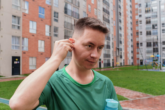 Man inserting earbud before urban exercise workout - Powered by Adobe
