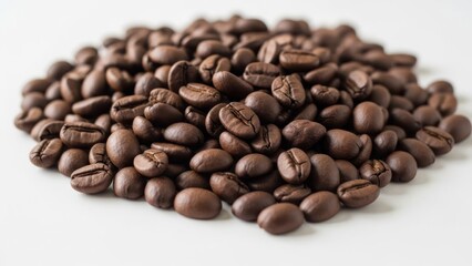 Fototapeta premium A close-up shot of a pile of roasted coffee beans, mostly in focus, on a white surface