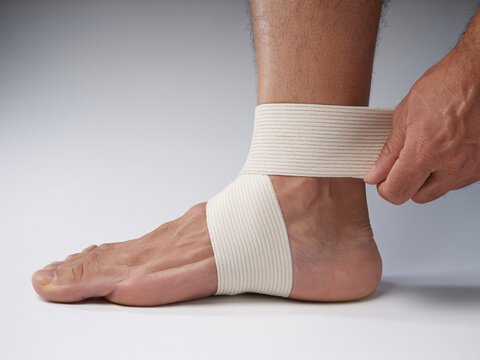 Securing injured ankle with elastic bandage for support, aid recovery, athletic taping for injury prevention, strain relief, and improved circulation