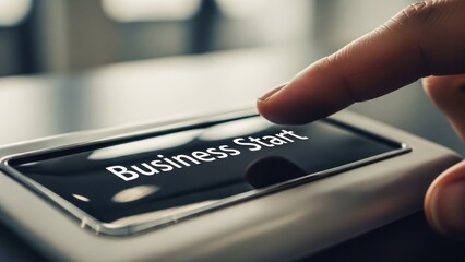 Finger pressing "Business Start" button on a device, close-up with shallow focus