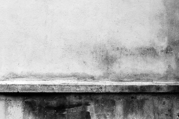 Textured concrete wall with black stains and horizontal ledge