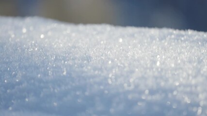 A close-up view of fresh snow shows tiny ice crystals sparkling in soft sunlight, creating a delicate winter texture across the smooth, frosted surface. - Powered by Adobe