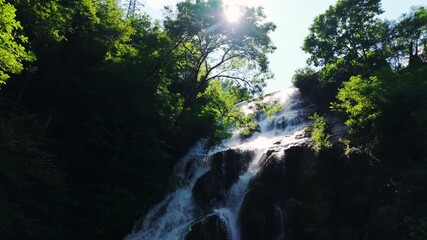 Serene waterfall in Italian Alps, sunlight creates tranquil nature vibe