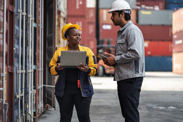 Man and woman logistics workers in high visibility safety gear discuss operations and checking container at shipping container yard	