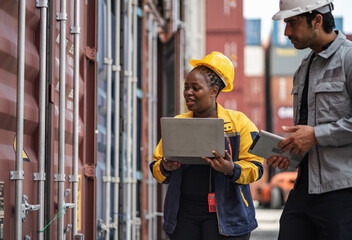 Man and woman logistics workers in high visibility safety gear discuss operations and checking container at shipping container yard	