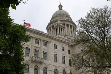 Naklejka premium Rhode Island State House dome framed by green trees on a cloudy day