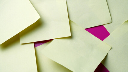 Yellow paper note on pink background. Texture background of sticky note stacked on each other. Abstract, installation, working, mess up, pages concept for wallpaper, background. Paper texture display.
