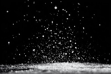 White particles falling against a black background. Abstract image with many tiny specks