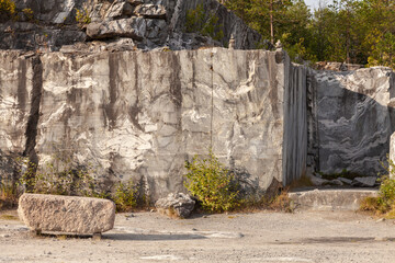 Marble quarry wall with stone block and small bushes
