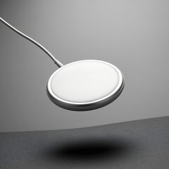 Modern wireless charging pad with metallic rim and power cable on a neutral background