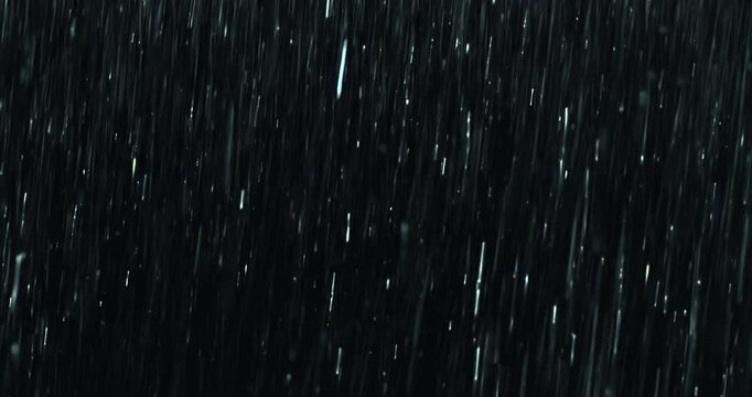 Heavy rain pours against a black background with close-up droplets splashing on impact. A seamless, loopable practical VFX element perfect for storm atmospheres, dramatic scenes and cinematic overlays