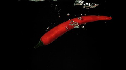 Red chili peppers fall under water. Filmed on a high-speed camera at 1000 fps. High quality FullHD footage - Powered by Adobe