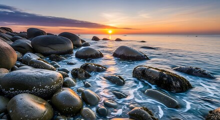 Sunset over a rocky coastline with waves washing ashore.