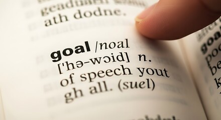 Finger points to the word "goal" in a dictionary.