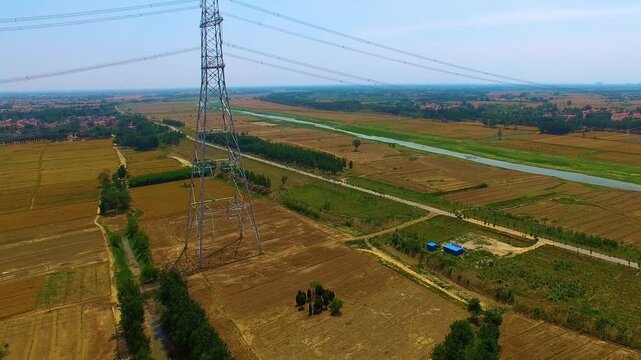 High Voltage Transmission Tower Over Agricultural Fields - Aerial View