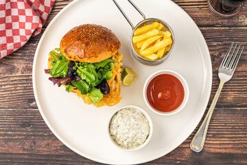 Crispy fried chicken burger served with fries and creamy dips