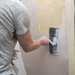 A man plastering a wall with a spatula