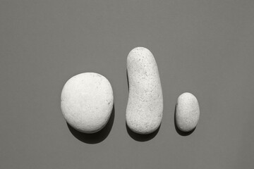 Three white smooth stones on a beige background. Top view, place for text. Color of the Year 2026, Cloud Dancer.