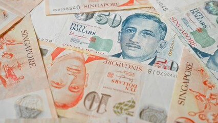 Singapore dollars banknotes spread across the surface, showcasing different denominations including...