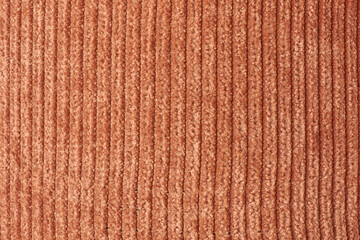 close-up of brown corduroy fabric with vertical ribbed pattern, soft rust-colored textile background, cozy material for clothing or upholstery in detail view