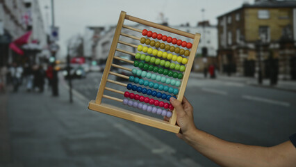 Man holding colorful abacus on a busy city street showcasing urban education and creativity amidst a bustling outdoor environment.