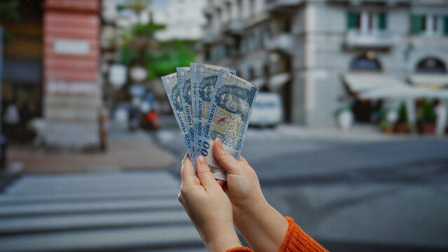 Woman holding hungarian forint banknotes in urban city street showcasing business and currency exchange outdoors, highlighting economic transactions and financial activities.