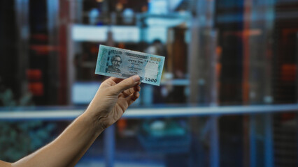 Person holding bangladeshi taka banknote indoors at a hotel reception, showcasing currency exchange...