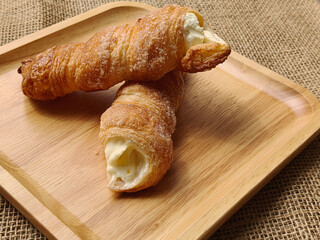 Cream horn bread pastries arranged on a wooden board, viewed from the side.