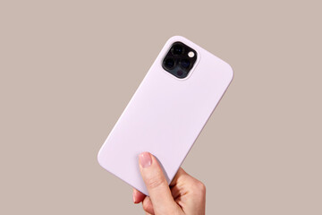 Hand holding sleek purple smartphone featuring multiple camera lenses against a worm gray background, highlighting modern mobile technology design elements Cloud Dancer color of 2026 year