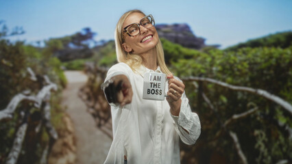 Naklejka premium Woman points finger and holds mug reading i am the boss in a forest setting; confidence empowerment leadership.