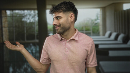 Man gesturing palm by modern building indoor spa pool with relaxed posture; welcome comfort relaxation.