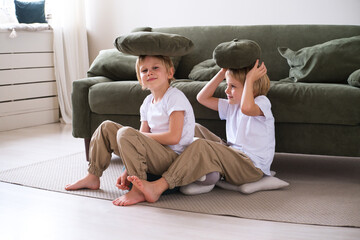 kids boys have fun with pillows, sitting on the living room floor