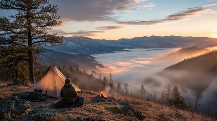 Traveler sitting by campfire near tent overlooking mountain valley filled with morning mist and sunrise light perfect for adventure lifestyle and outdoor exploration themes