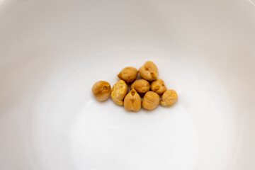 Few dry chickpeas in a white bowl. Minimal food concept showing raw legumes used for cooking,...