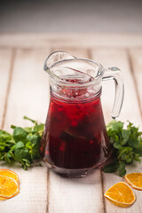 Cold refreshing berry drink with ice citrus slices and fresh mint served in clear glass pitcher