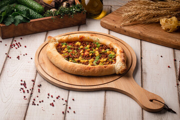 Traditional khachapuri baked with savory minced meat filling and vegetables served on a wooden board
