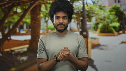 African american man expressing gratitude in a green outdoor park on a sunny day, showcasing a heartfelt gesture.