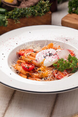 Spicy penne arrabbiata pasta with tomato sauce, vegetables and soft poached egg served on a white plate