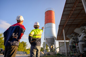 Two engineers evaluating the concrete plant structure, checking silo conditions and workflow efficiency at an industrial concrete batching facility. © เลิศลักษณ์ ทิพชัย