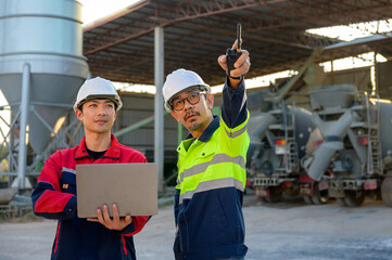 Engineer pointing and explaining operational details at a concrete plant, highlighting safety, communication, and industrial workflow.